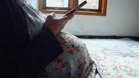 Pregnant woman typing on smartphone in home, reading email notification and social media, pregnancy research online. Pregnancy,  and search for baby news, scroll website or mobile app
 - Powered by Shutterstock - Get 15% off with code: PIKWIZARD15