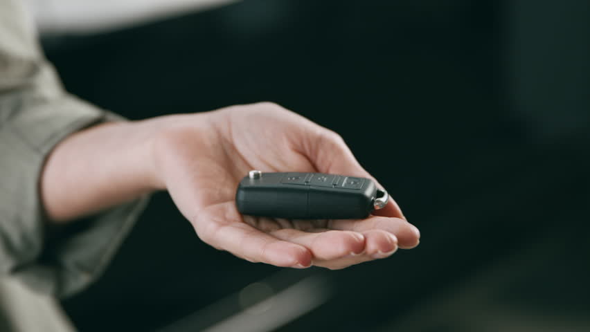 A customer is receiving car keys from a salesperson in an auto salon