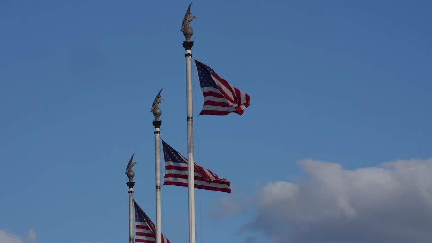 American flag waving in blue sky. Symbol of freedom and national pride. Red white and blue colors of unity. Patriotic scene representing democracy and strength. U.S. flag flying.