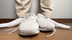 Close up of a woman putting on white sneakers and tying shoelaces indoors. Preparing for fitness, workout, jogging, training, or casual activity on wooden floor - Powered by Shutterstock - Get 15% off with code: PIKWIZARD15