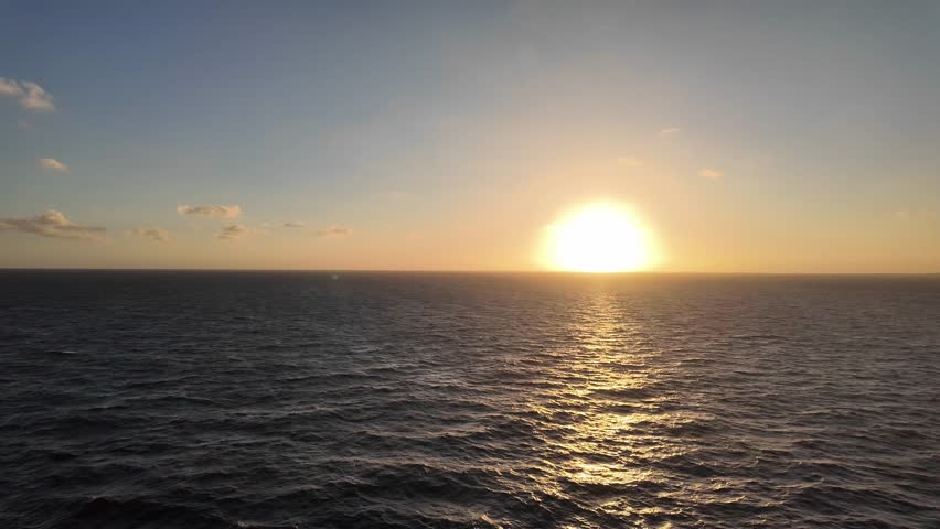 Beautiful sunset over calm ocean waves. Golden sunlight reflecting on sea surface. Peaceful evening view of endless horizon. Warm glow of nature and tranquility. Serene seascape during golden hour.