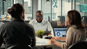 Diverse coworkers in meeting discuss strategy and budgeting, forecasting plans for efficiency. Corporate team evaluates performance metrics, reports and files for resources allocation. Camera B. - Powered by Shutterstock - Get 15% off with code: PIKWIZARD15