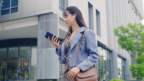 Young business businesswoman walking outdoor, happy professional travel near modern office buildings, using smartphone with earphones, enjoying urban environment and digital connection. - Powered by Shutterstock - Get 15% off with code: PIKWIZARD15