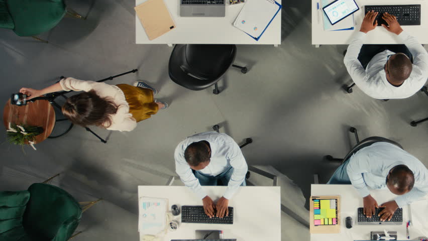 Top down view zoom out of coworkers broadcasting an advertising vlog for marketing content, reviewing documentation and insights. Professional office forecasting within corporate. Camera A.