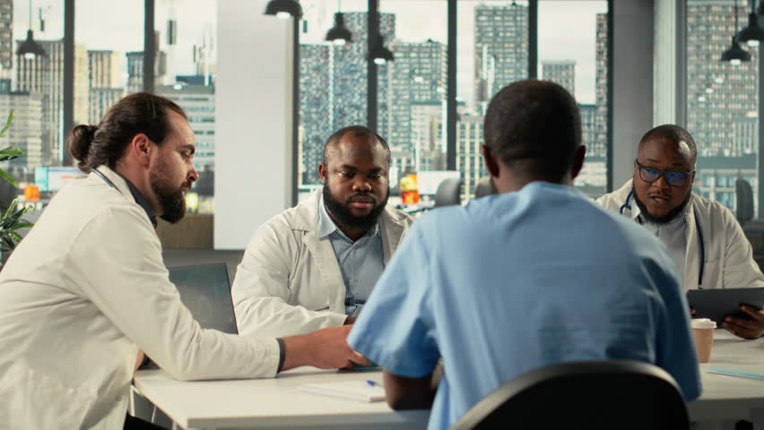 Surgeons and medical staff in a clinic discussing therapy options and research analysis. The meeting highlights professionalism, coordination and innovation in healthcare planning. Camera B.