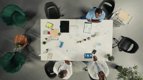 Top down view zoom in of physicians and medics gathered for briefing conference. Group discusses healthcare advancements, laboratory research and treatment methods to enhance medical care. Camera A. - Powered by Shutterstock - Get 15% off with code: PIKWIZARD15
