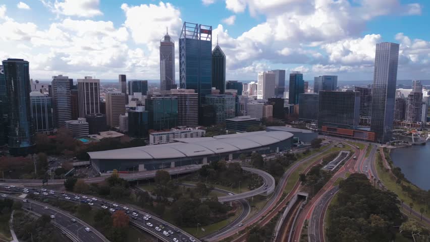 Aerial footage of the Perth CBD Skyline, with heavy traffic on the Mitchell Freeway on a bright, cloudy afternoon in Perth, Western Australia.