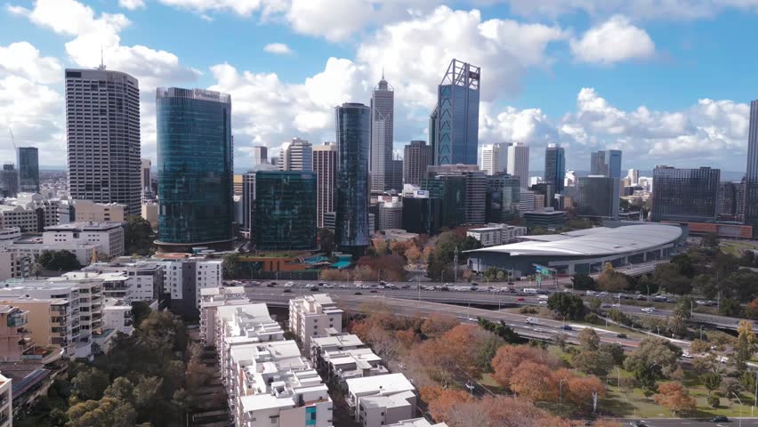 Spectacular aerial footage of cars on the Mitchell Freeway, with the Perth CBD Skyline in the background on a bright and cloudy afternoon in Perth, Western Australia.