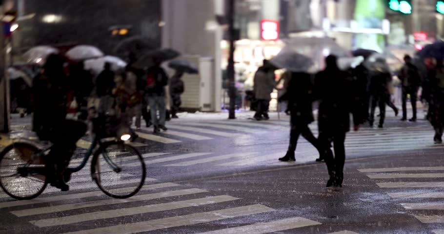 Walking people at business town in Shinjuku snowy day handheld at night