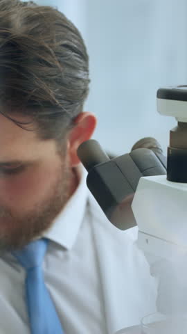 Scientist, man and analysis in lab with microscope for sample inspection, biotech and stem cell research. Bokeh, person and equipment with science, medical innovation and cure development for cancer.