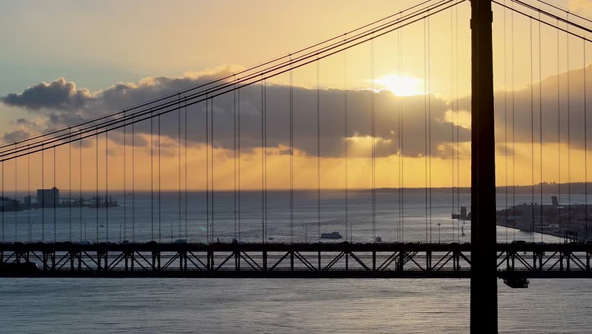 Sunset Sky Over 25 Of April Bridge At Lisbon In Lisbon District Portugal. Sunset Downtown. Freeway Road Landscape. 25 Of April Bridge At Lisbon In Portugal. Public Transport Scenery.