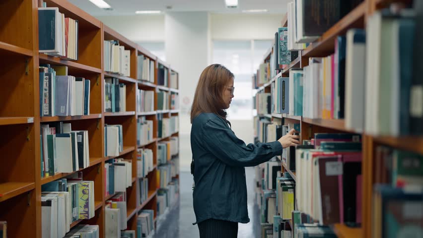 Asian female student selects books for reading in library at university. Knowledge and wisdom, Learning and education concept