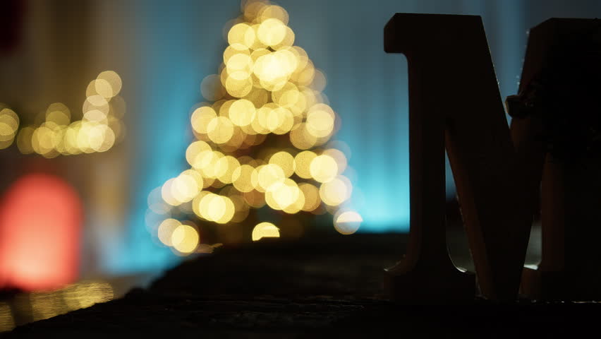 Merry Christmas Lettering In Silhouette In Front Of Christmas Tree