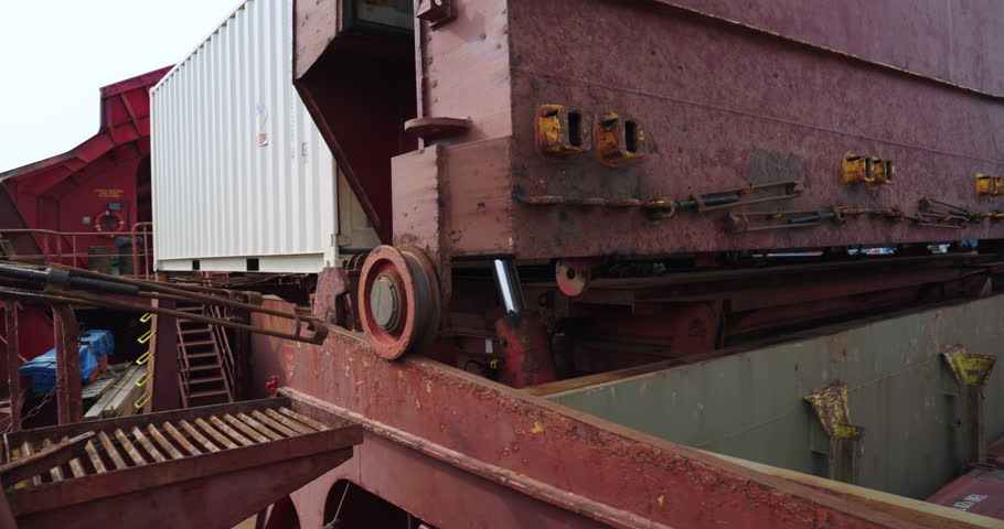 Industrial plate feeder transports granular material. Mechanical rhythm echoing through steel hall. Machinery hums with precise tempo