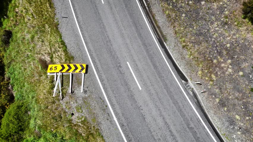 Aerial view of a gleaming silver truck contrasting against the gray asphalt on River Road surrounded by green vegetation, Hanmer Springs, Canterbury Region, New Zealand.