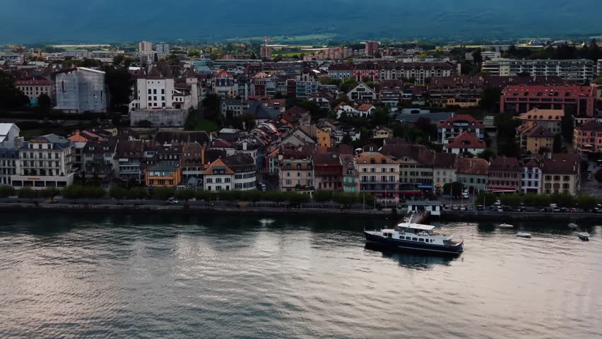Aerial view of the serene waters of Lake Geneva, with buildings lining the shore under a cloudy sky, Lake Geneva, Vaud, Switzerland.