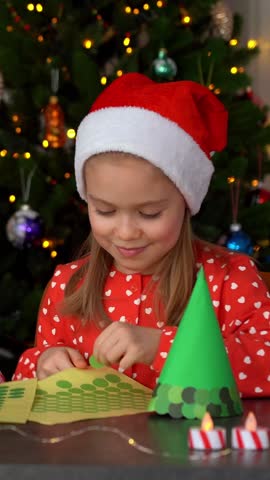 Happy girl make Christmas tree diy from green paper for Christmas holidays. Childrens leisure. Craft handmade. Vertical shot