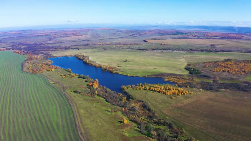 An aerial shot captures the serene landscape of Lake Alashskoye, located near Shihan Juraktau in the South Ural region of Russia. The footage shows the deep blue water of the lake surrounded by a patc