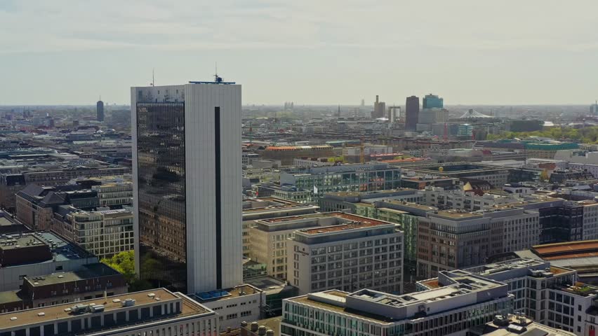Aerial view of modern skyscrapers reflecting the sky amidst a dense urban landscape of buildings in the city, Berlin, Berlin, Germany.