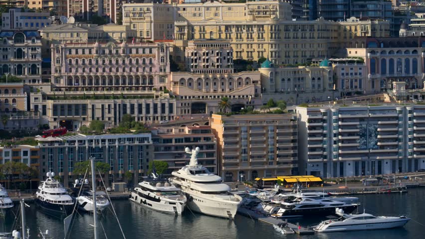 La Condamine, Monaco – August 25, 2024: View of multiple luxury boats and yachts docked in Port Hercules with Monte Carlo’s cityscape and blue Mediterranean waters.
