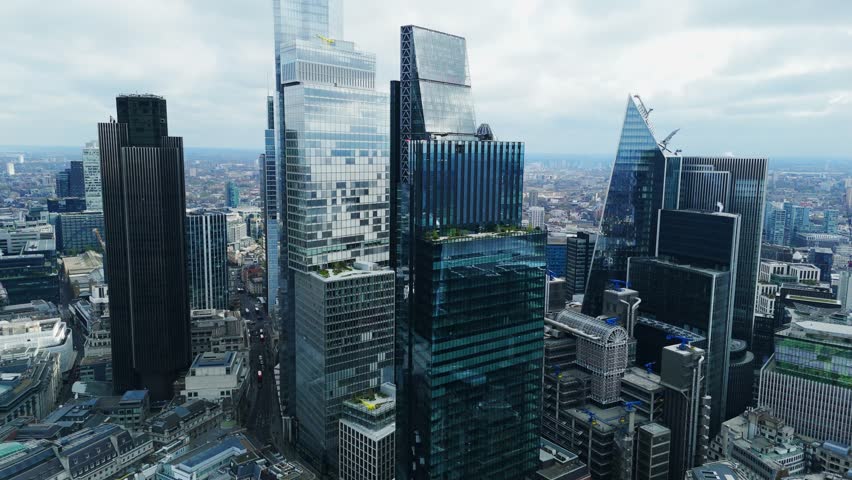 Aerial view of towering skyscrapers piercing the skyline, reflecting the muted sky above, a modern metropolis of glass and steel, London, United Kingdom.