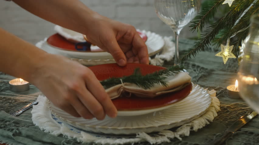 Female hands set the table, preparing dishes for a festive Christmas dinner