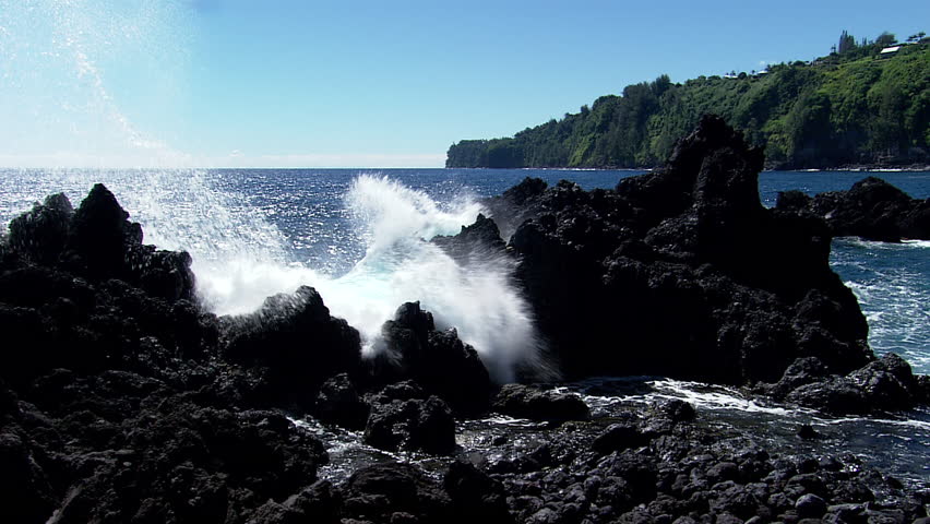 Waves crash in to rocks on the coast of Hawaii's cliffs