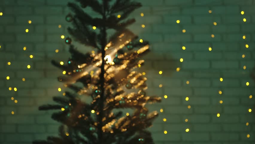 A festive scene featuring a Santa Claus figure holding a wrapped Christmas gift with a red ribbon in front of a beautifully lit Christmas tree.