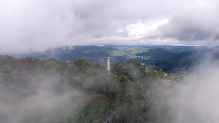 A dramatic drone shot shows the Point Park statue framed by swirling fog with sweeping views of Lookout Mountain and the valley beyond.