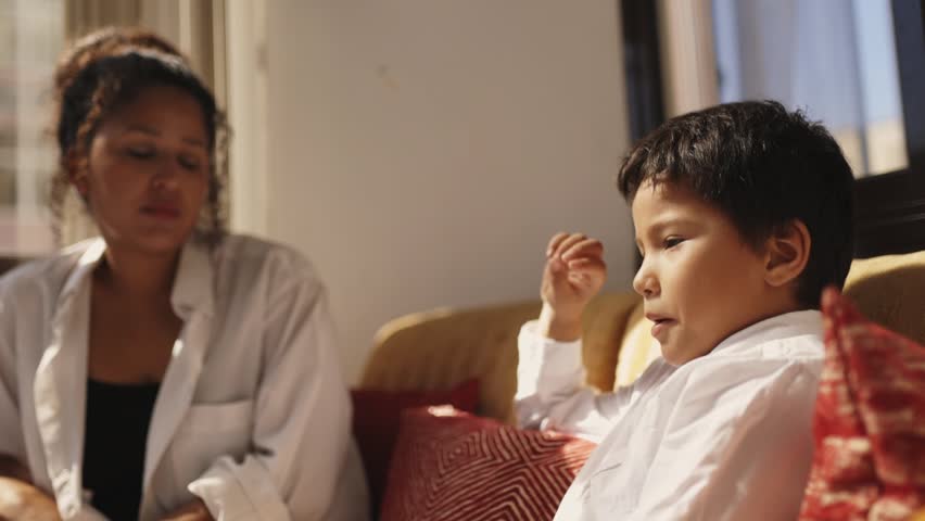 Young boy explaining something to his babysitter on the sofa