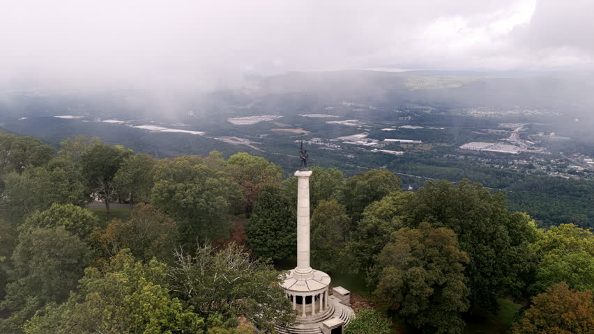 An elevated view captures the Point Park monument rising from the treetops as clouds lift to reveal the Tennessee landscape below.