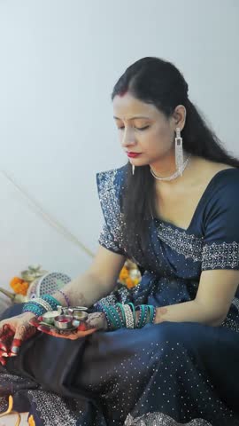 Indian woman in blue saree offering puja with traditional thali during festival