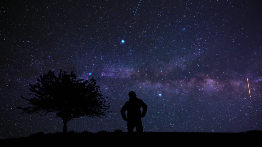 Silhouette of a man and countryside under the Milky Way stars.