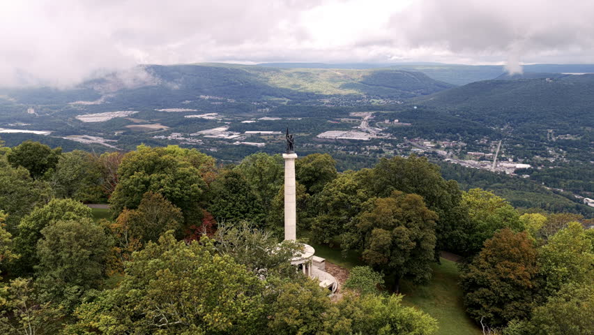 The Point Park statue stands tall above the trees, overlooking the Tennessee Valley and distant ridges under breaking clouds.