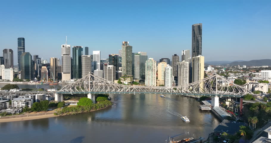 4K aerial push-in tracking motion view of the iconic Story Bridge and east side of Brisbane CBD with Brisbane River below where  CityCat ferries commute passengers, Brisbane, Queensland, Australia