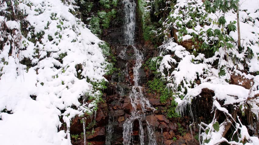 This aerial footage captures the winter beauty of Turkey — a small waterfall flowing through snowy rocks and forests, creating a calm and peaceful natural scene.
