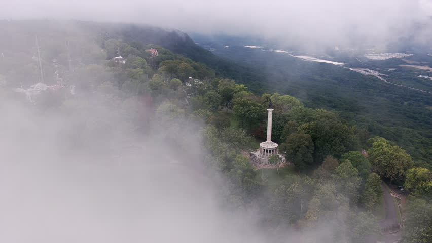 Fog drifts across Lookout Mountain as the Point Park monument emerges through the clouds, surrounded by lush Tennessee forest.