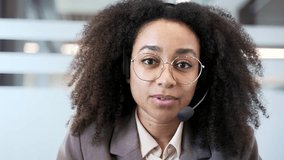 Webcam view. Smiling african american businesswoman in headset talking on video call conference looking in camera sitting in business office. Female manager communicates at online meeting. Close up - Powered by Shutterstock - Get 15% off with code: PIKWIZARD15