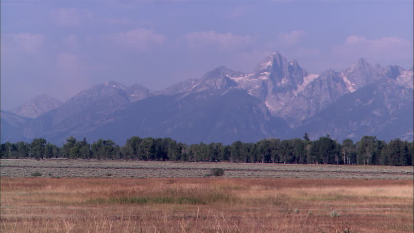 A wide open valley with large mountains in the background as seen during the day
