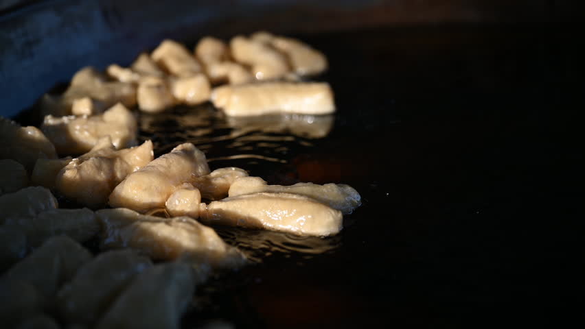 Deep fried dough stick grilling on BBQ Strove. Asian very famous snack called youtiao in Singapore or white sugar sponge cake grilled by chef. 