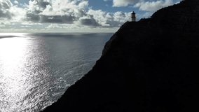 Aerial drone footage of a lighthouse perched on Oahu’s windward coast cliffs, Hawaii, showcasing dramatic rocky coastline, turquoise ocean waves, lush tropical vegetation, and panoramic ocean views. - Powered by Shutterstock - Get 15% off with code: PIKWIZARD15