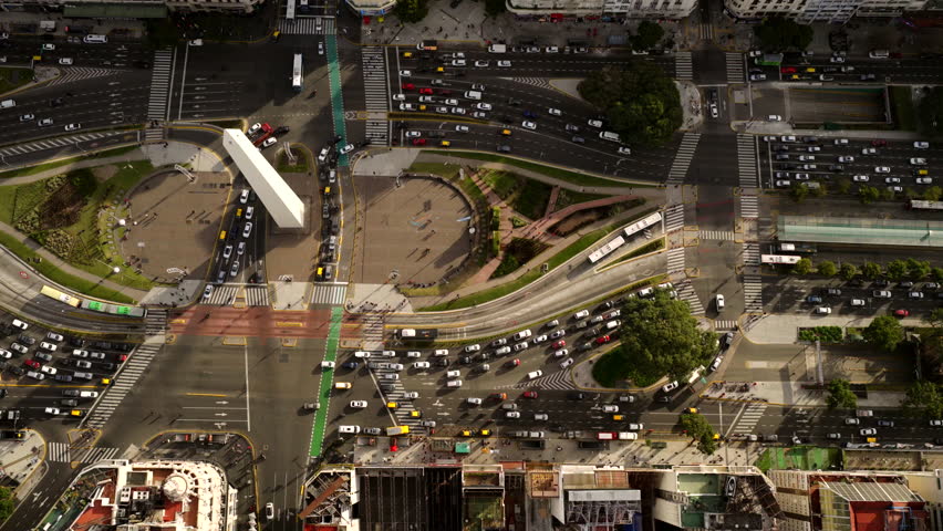 Top-down aerial view of traffic and the Obelisco monument at Avenida 9 de Julio in Buenos Aires.