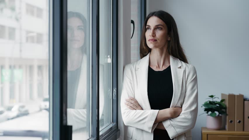 Video of beautiful businesswoman taking a break while looking forwards to the window at the office.