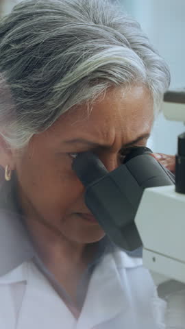 Scientist, woman and microscope in lab for biotech, sample inspection and stem cell research. Bokeh, mature person or science expert with equipment, medical innovation or cure development for cancer.