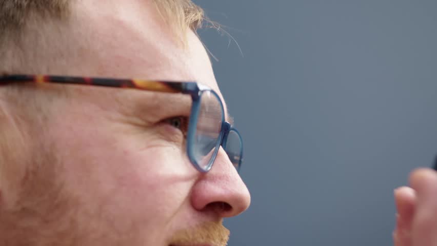 Side view close-up of a man with glasses raising a camera to his eye to take a photo. Captures a moment of focus, creativity, and the process of photography.