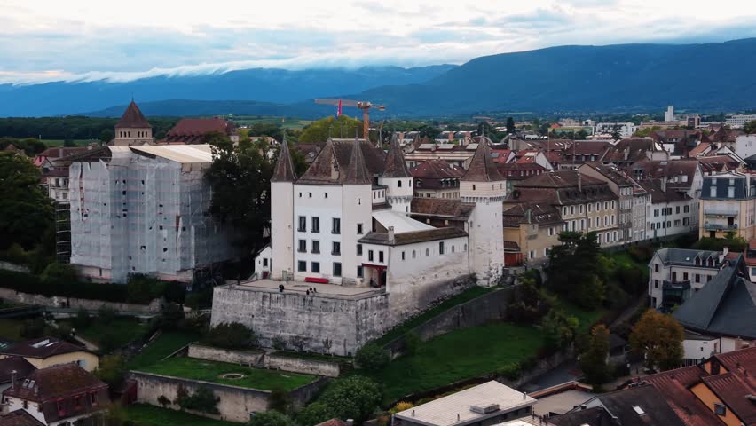 Aerial view of the medieval Nyon Castle with its white walls and red-tiled roofs, contrasting with the surrounding townscape, Nyon, Vaud, Switzerland.
