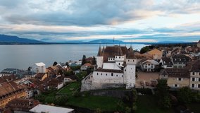 Aerial view of Nyon Castle with its towers and the flag, surrounded by a town near the lake under a cloudy sky, Nyon, Vaud, Switzerland. - Powered by Shutterstock - Get 15% off with code: PIKWIZARD15
