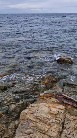 The sea waves roll onto the stone shore
