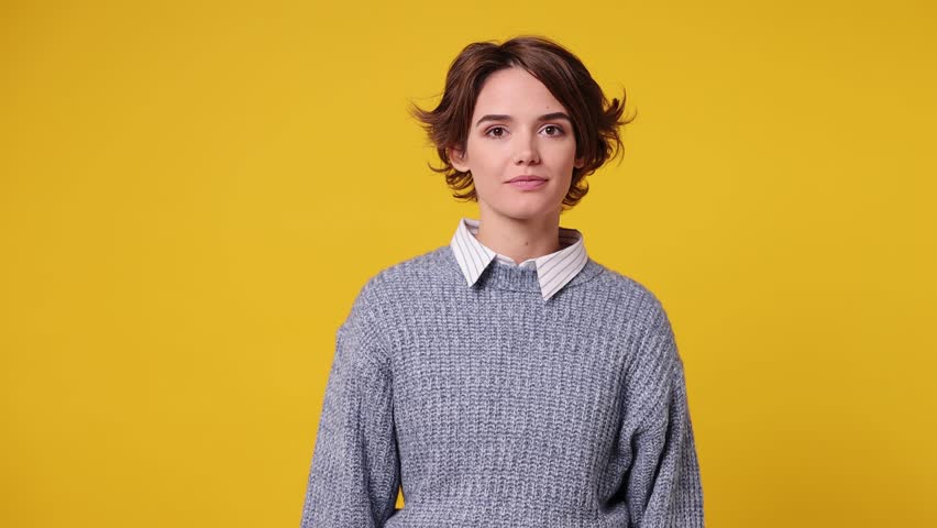 Happy young woman wears grey knitted sweater white shirt casual clothes hold fan of cash money in dollar banknotes do winner gesture celebrate isolated on plain yellow background. Lifestyle concept