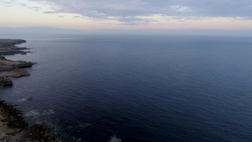Lighthouse on the cliff aerial view at dusk in England - Drone video of a white and red lighthouse at the edge of the Isle of Portland - Travel and architecture concepts